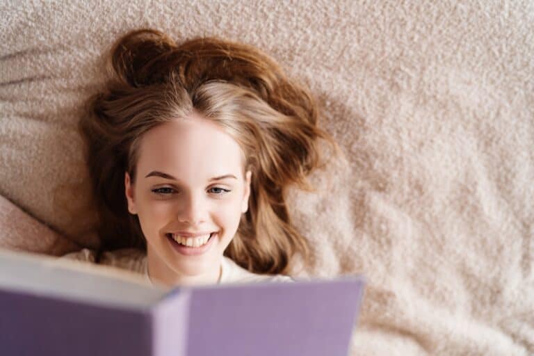 Young pretty girl on bed at home enjoying favorite book